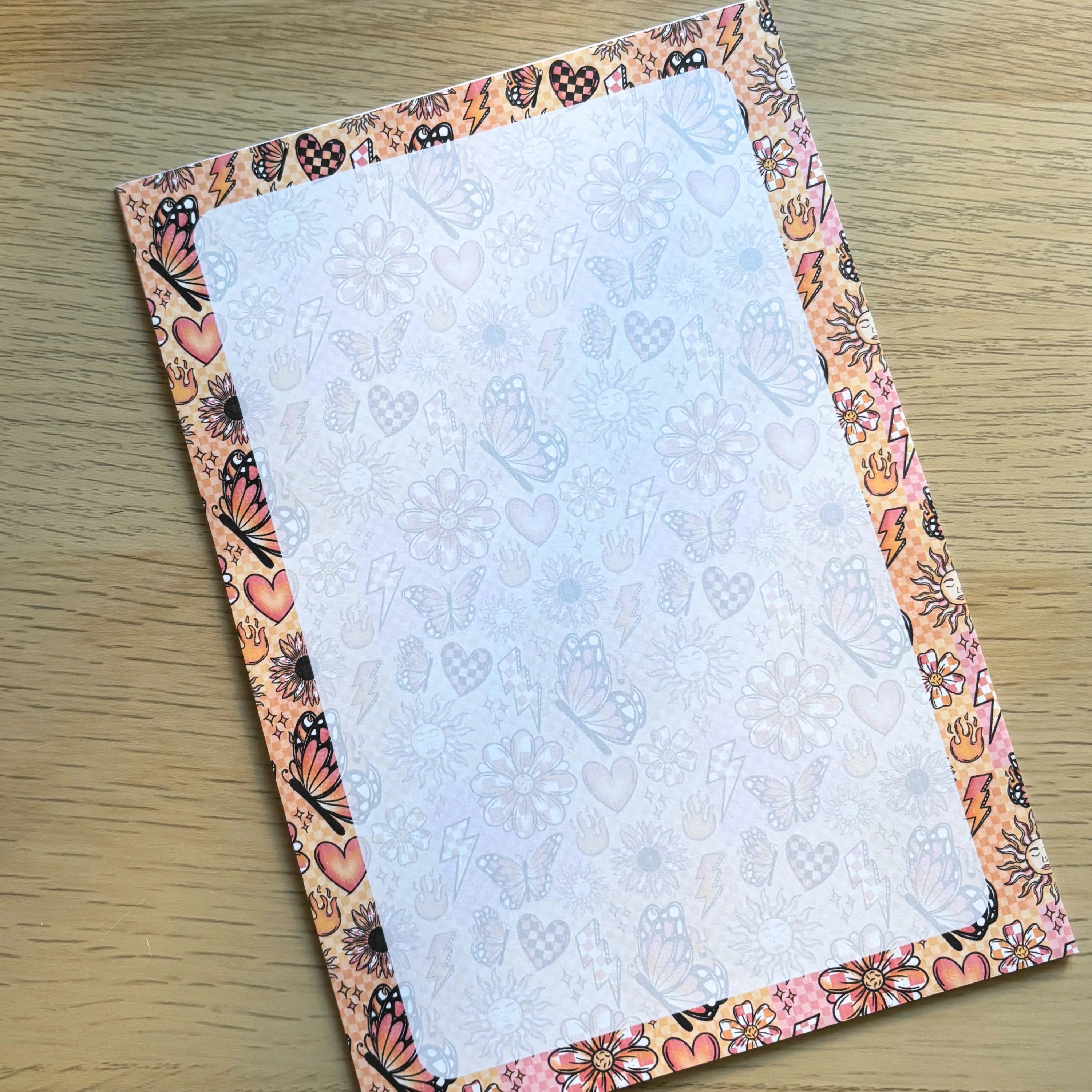 Small rectangular notepad with pastel butterfly and floral border and faint butterfly-themed lined pages.