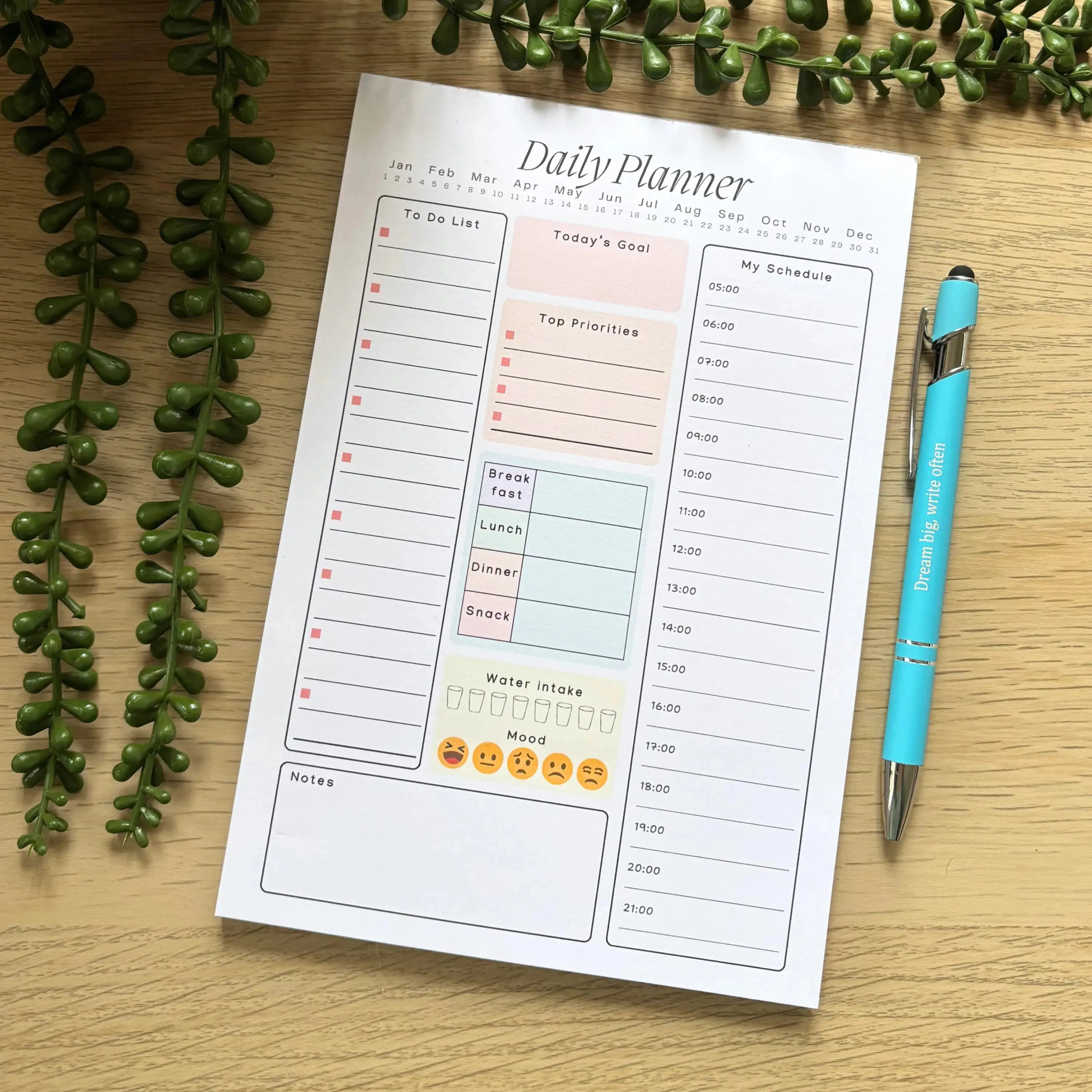 Daily planner notepad with pastel-colored sections for today's goals, to-do list, notes, and mood tracking on a wooden.