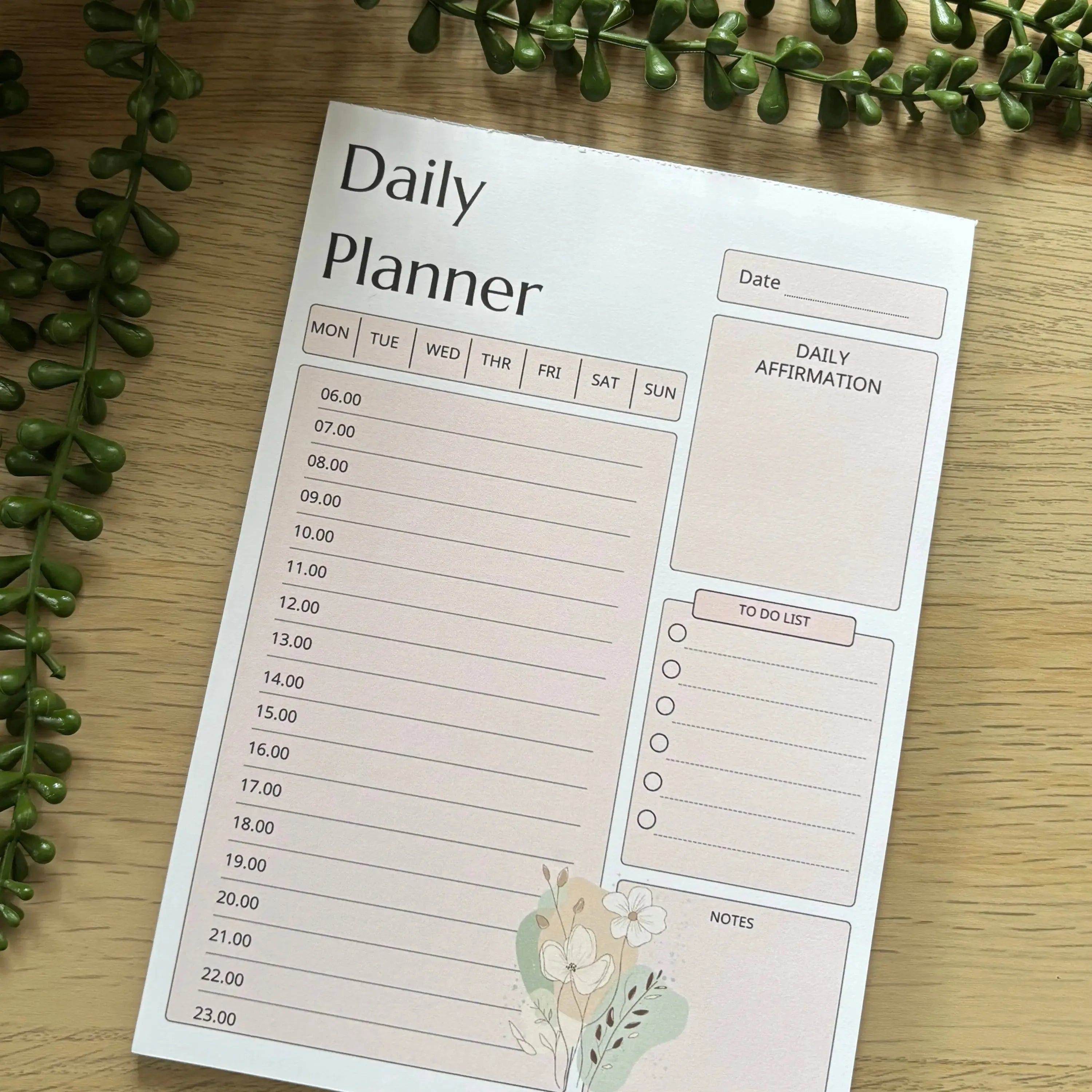 Minimalist pink daily planner notepad with hourly schedule, affirmation, to-do list, and notes sections.