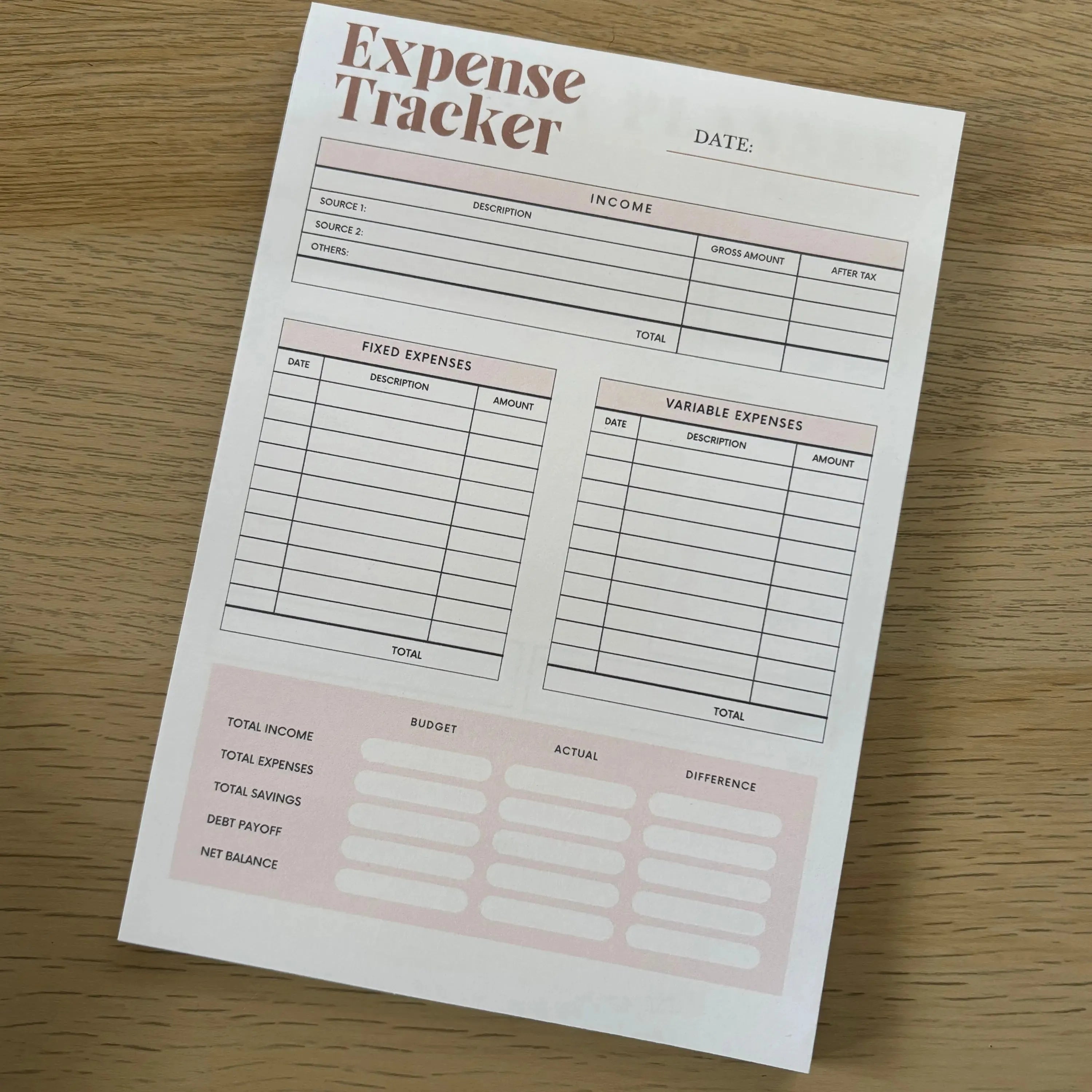 Minimalist Expense Tracker notepad with sections for date, fixed expenses, variable expenses, and notes on wood surface.