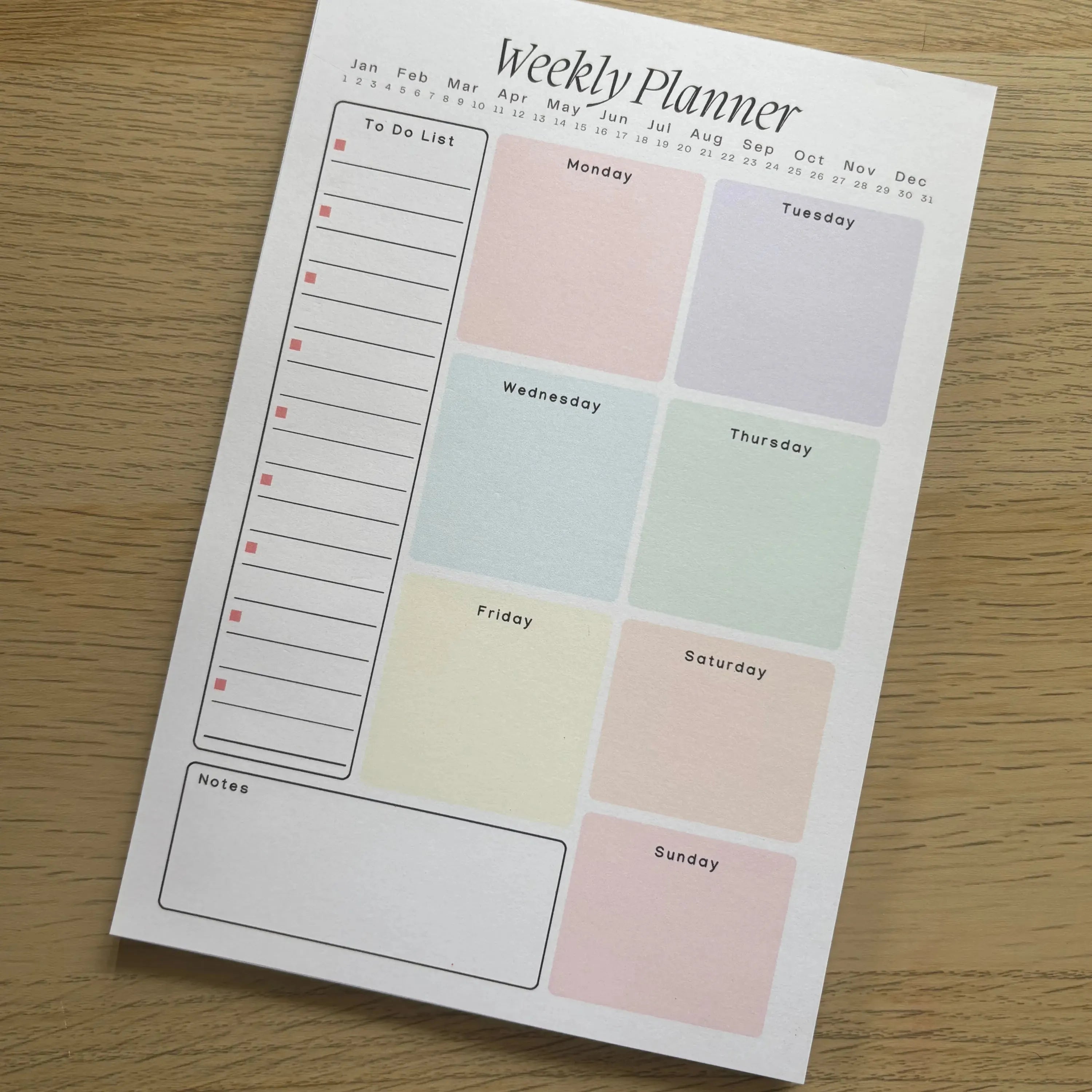 Pastel weekly planner notepad with minimalist layout, separate pastel-colored day blocks and a to-do list column on light.