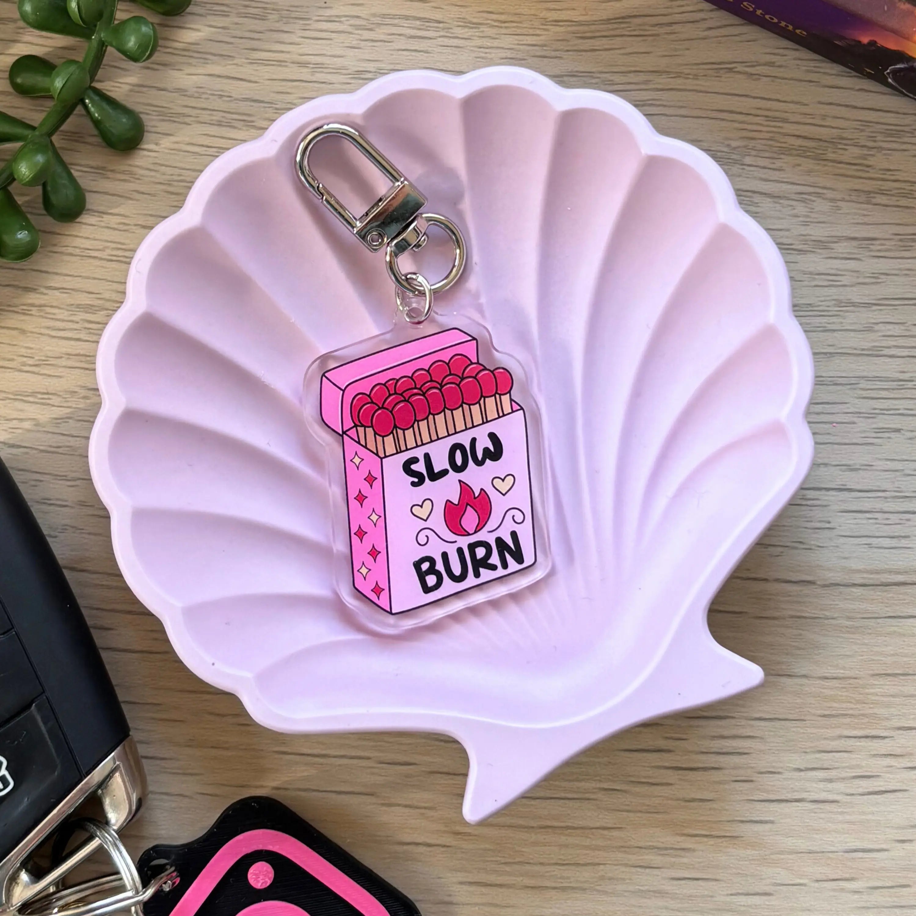 Pink enamel keyring shaped like a matchbox with "Slow Burn" text and heart designs.