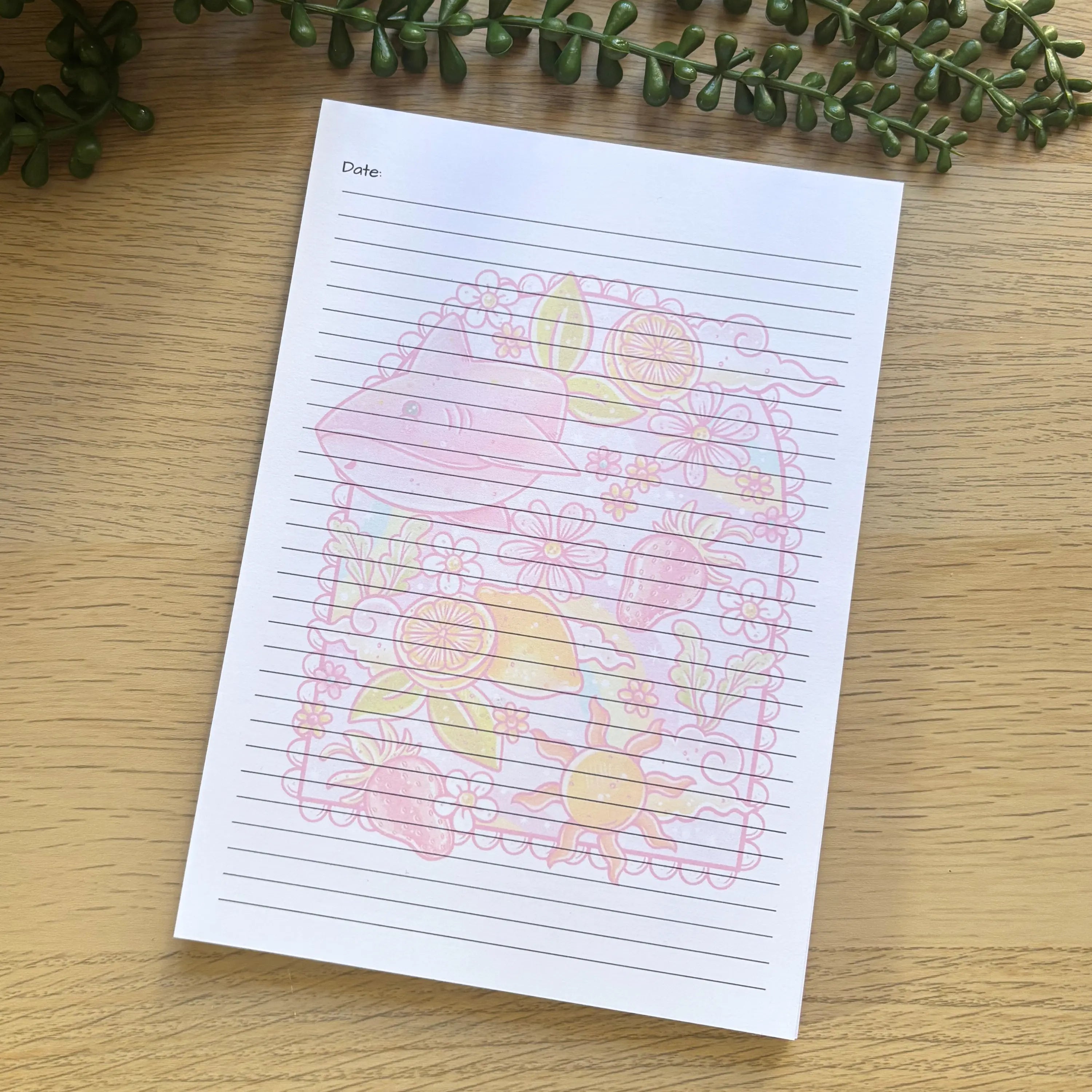 A5 notepad with lined pages and pastel floral and lemon illustration in the center.