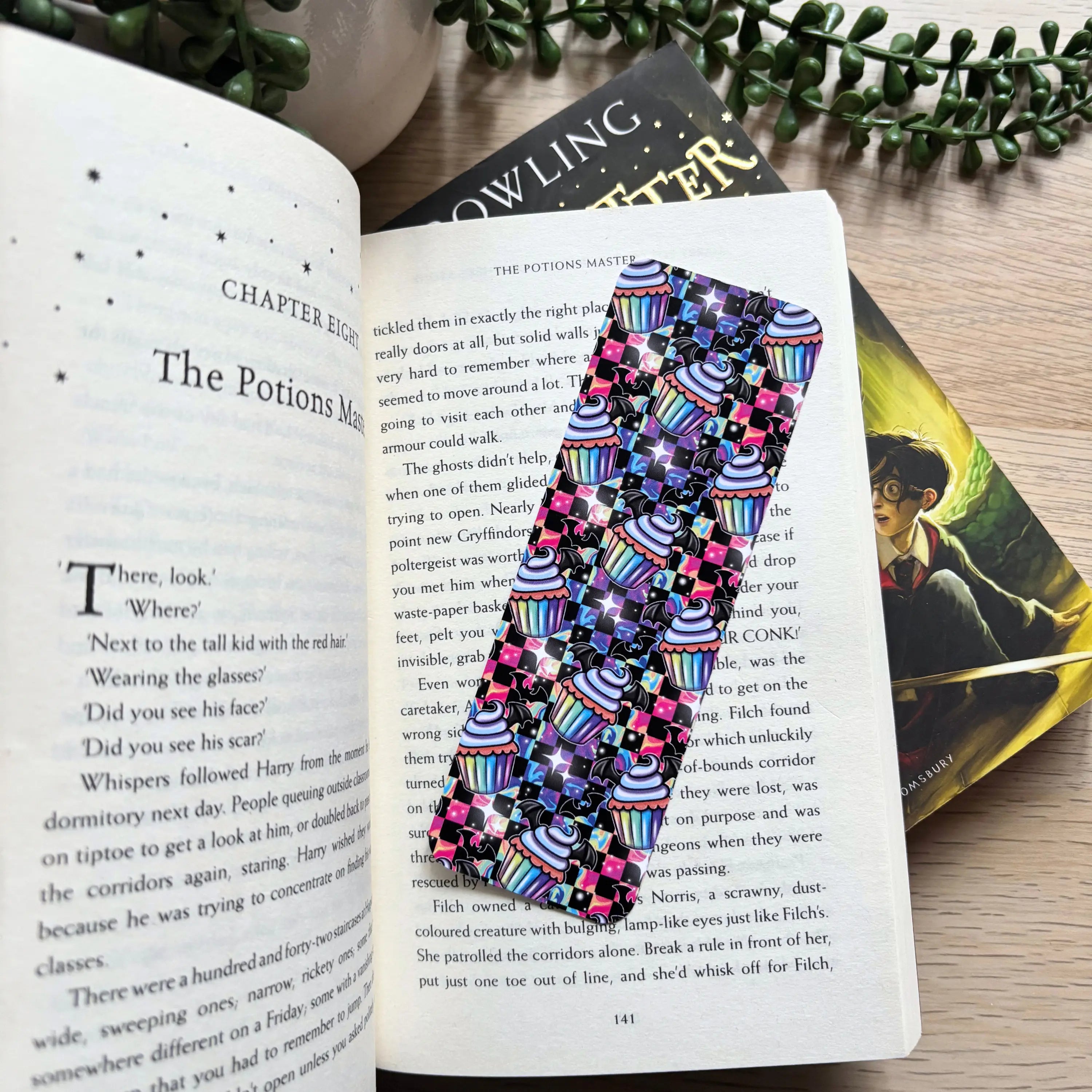 Colorful bookmark with kawaii gothic bat cakes and striped background on an open book page.