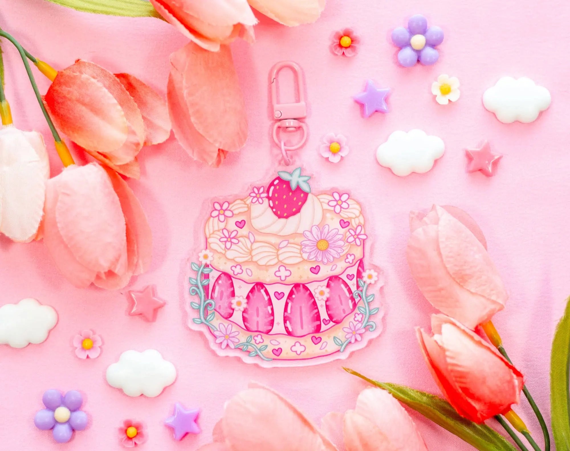 Decorative keychain with cake design surrounded by pink tulips and flowers on a pink background