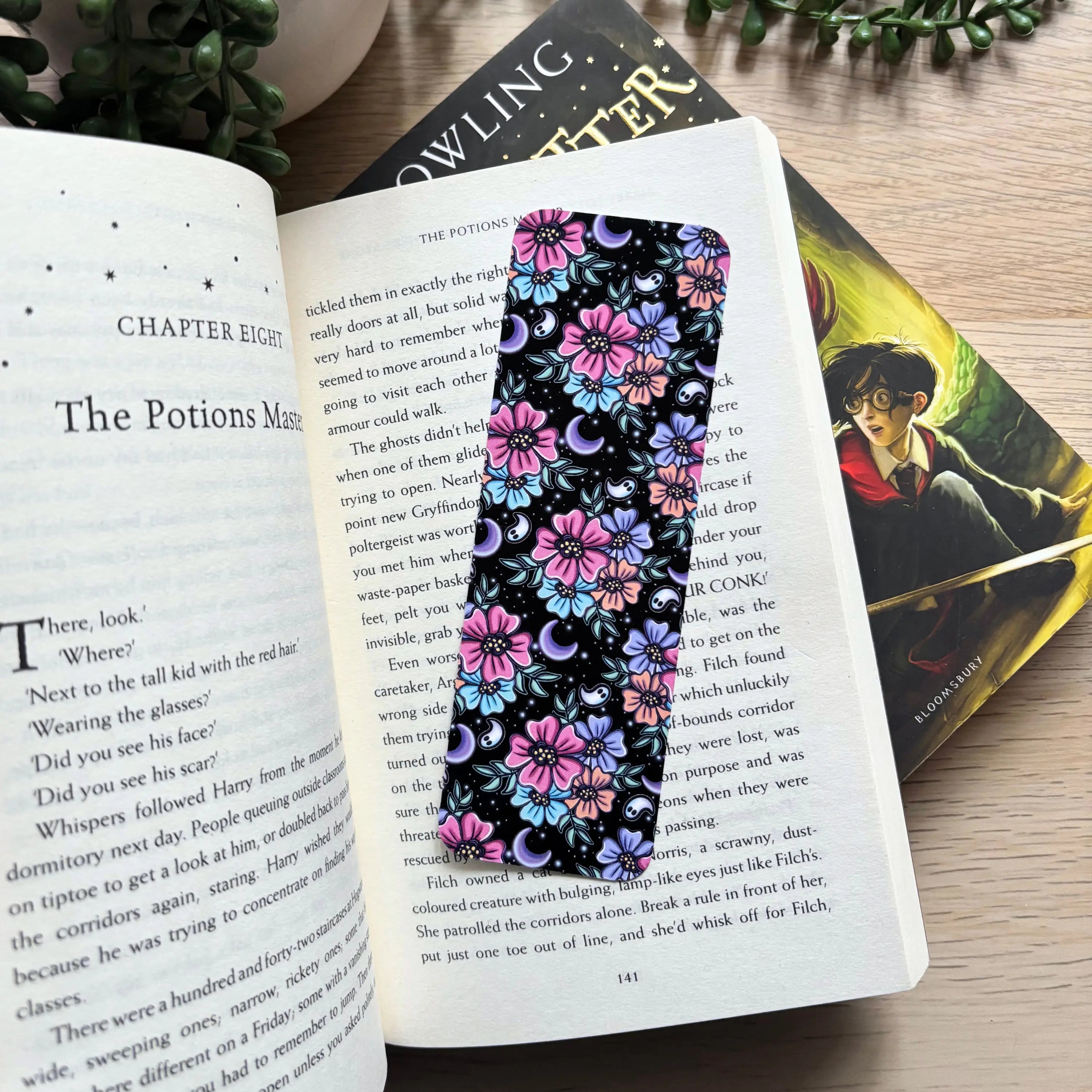 Floral night-themed bookmark with purple and pink flowers on black background placed inside an open book.