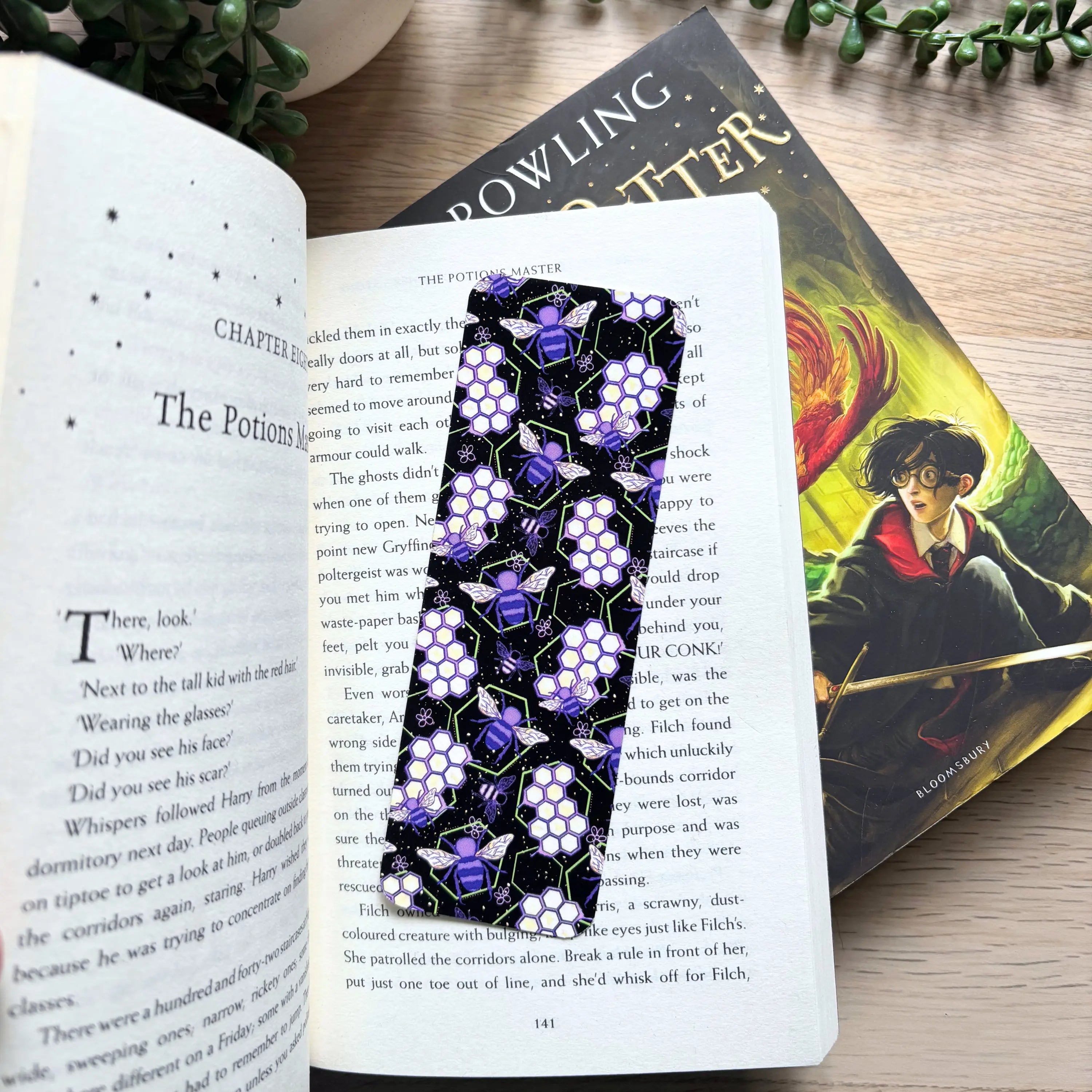 Black bookmark with neon purple and yellow bees and hexagonal honeycomb pattern.