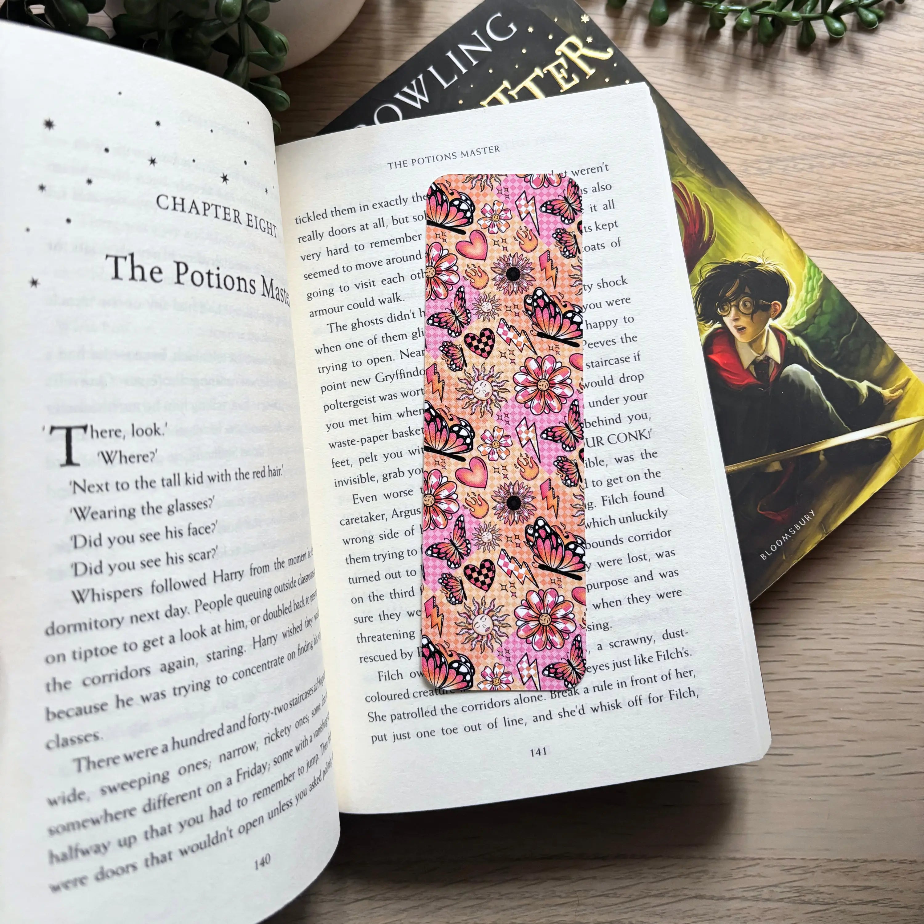 Vintage-style rectangular bookmark with pink background and colorful butterfly and floral patterns placed inside an open book.