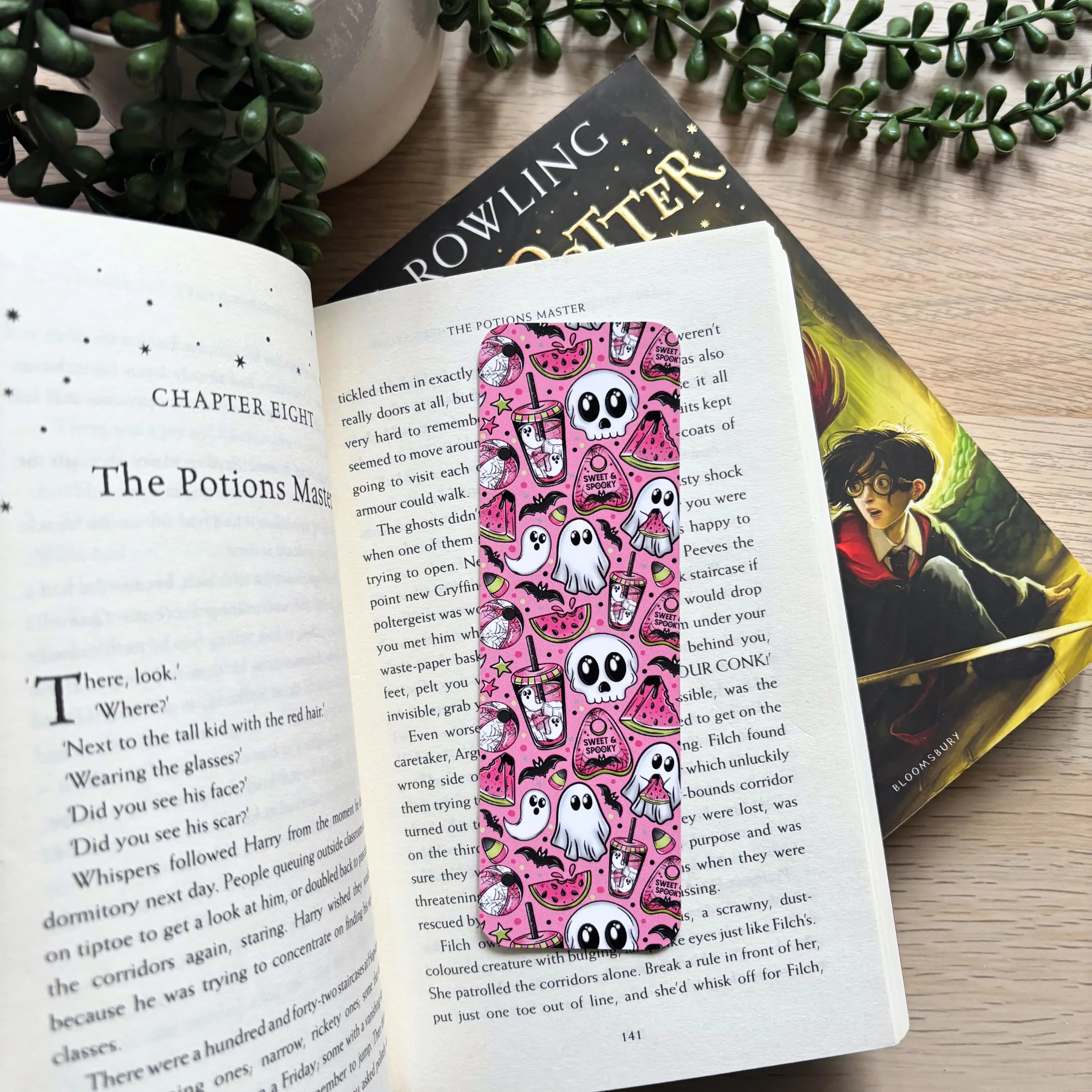 Pink bookmark with white skulls, ghosts, and black bats in a spooky, whimsical pattern.