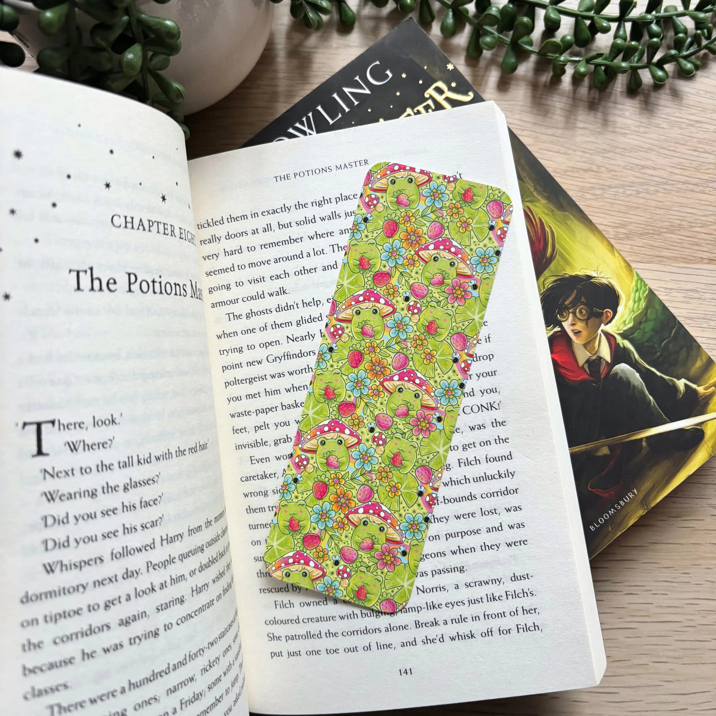 Pastel green bookmark with colorful floral pattern resting on open book pages.