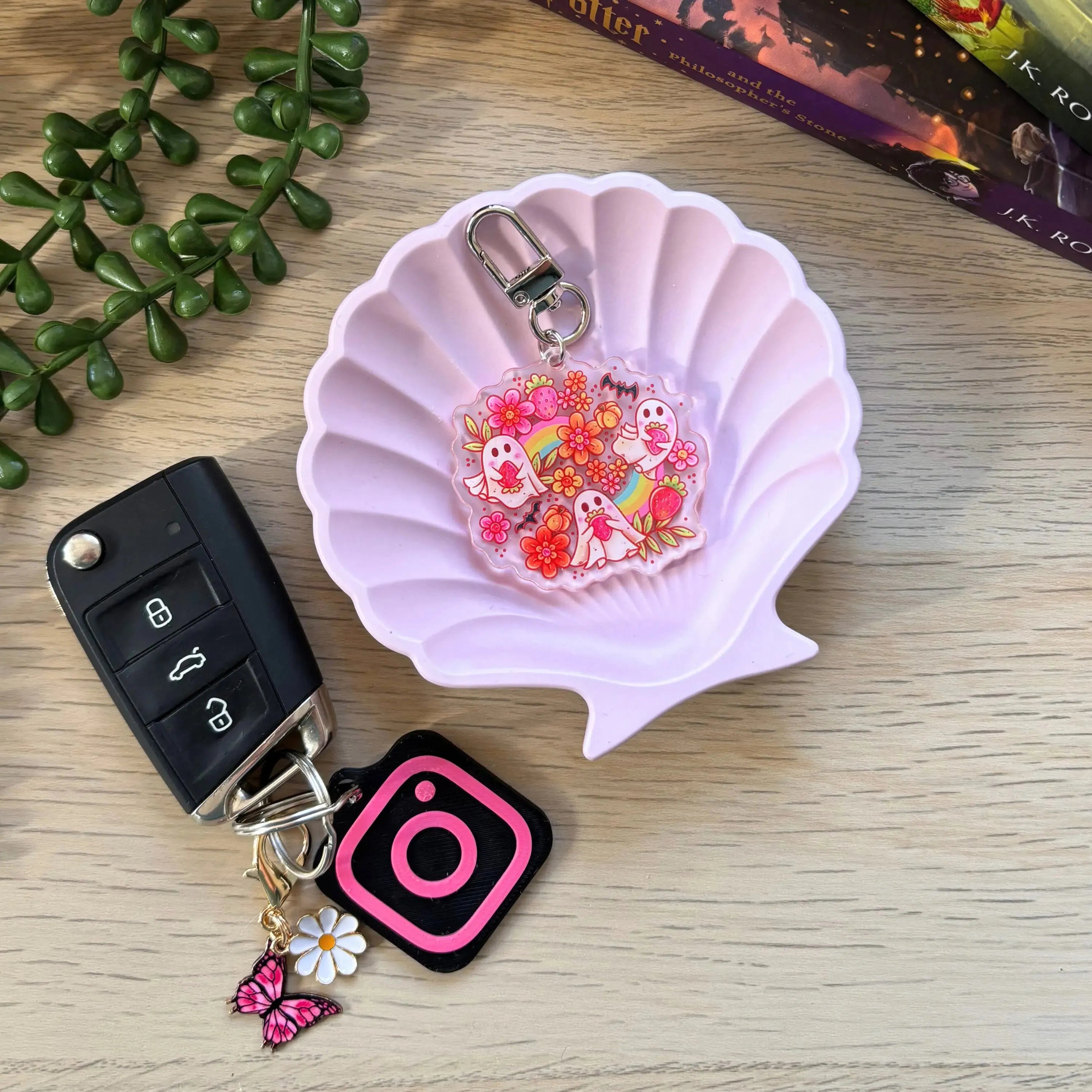 Pink translucent ghost keyring with strawberry and flower designs attached to a silver clasp, displayed in a light pink.