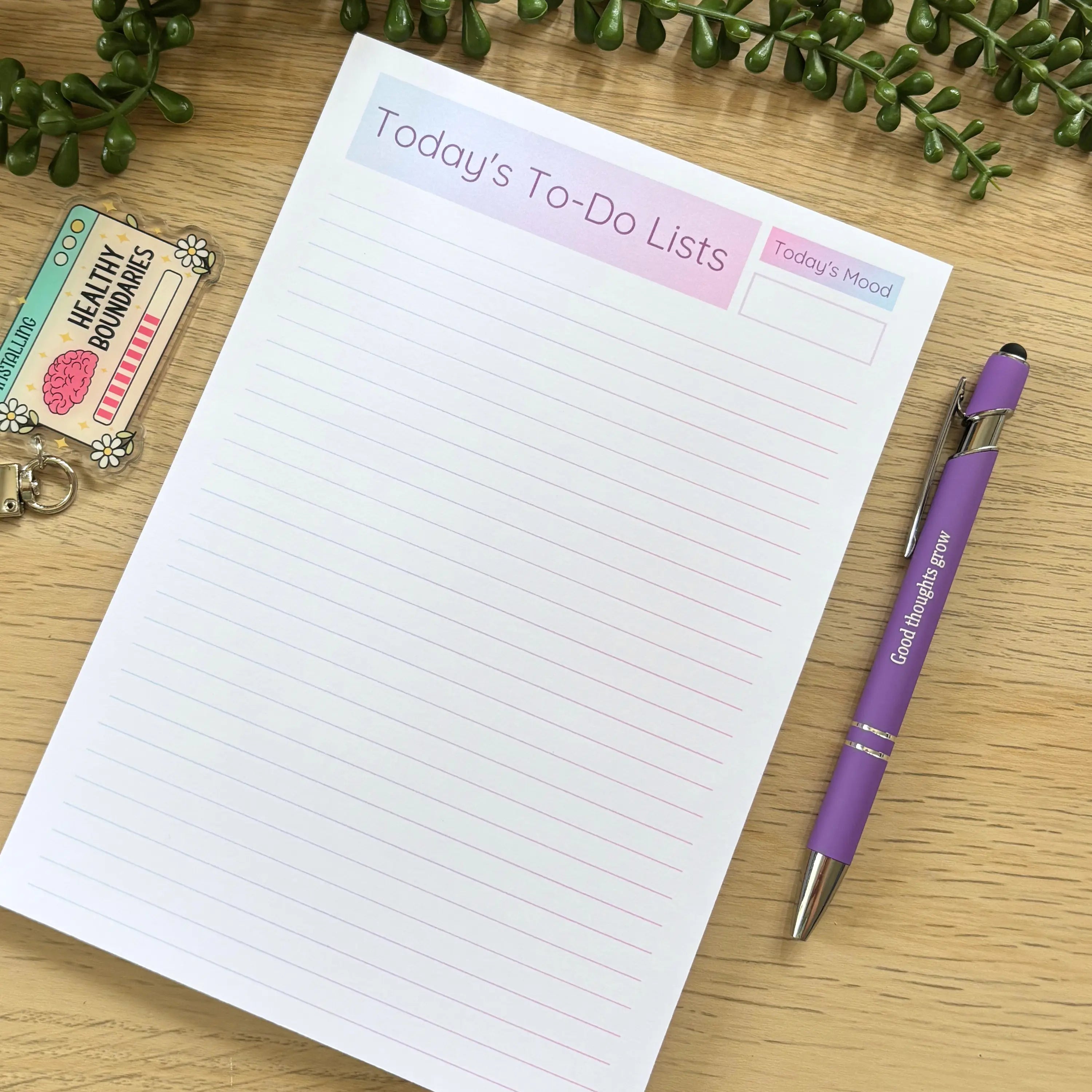 Minimalist to-do list notepad with pink ombre header and lined white pages on wooden surface with purple pen.
