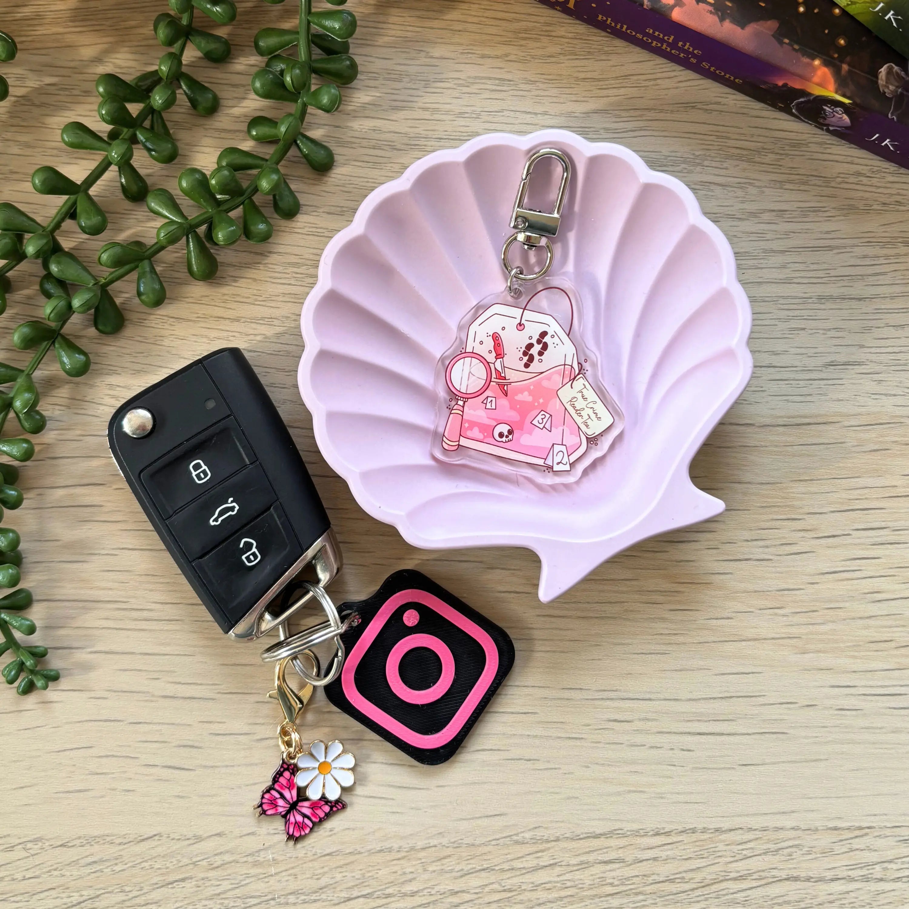 Pink teabag-shaped keyring with clock and "true crime reader" text, attached to a silver clip.